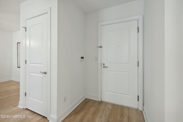 hall featuring light wood-style floors and baseboards