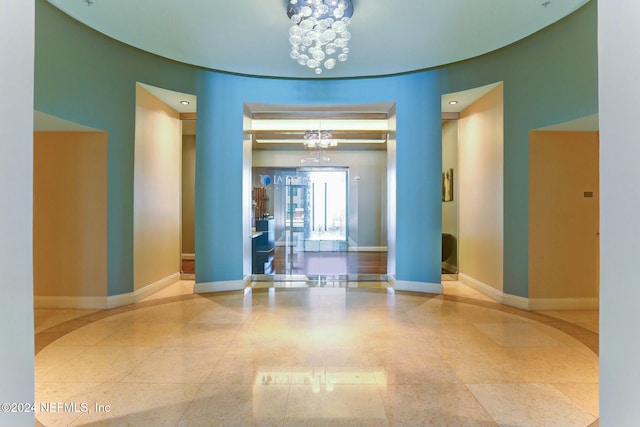 spare room featuring a chandelier and baseboards