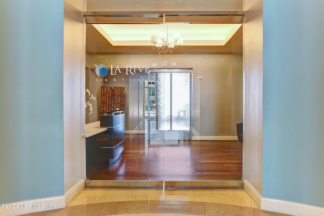 dining space with a tray ceiling, baseboards, and a chandelier