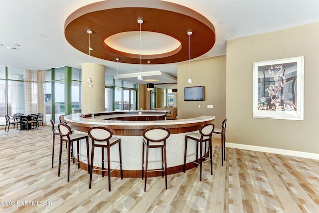 bar with baseboards, decorative light fixtures, and a tray ceiling