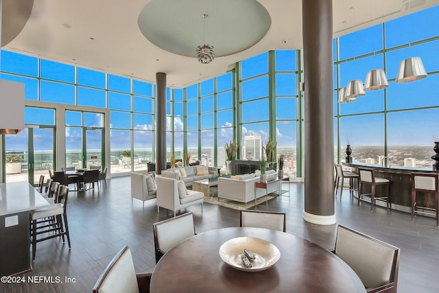 dining room featuring a towering ceiling, a wall of windows, decorative columns, and wood finished floors