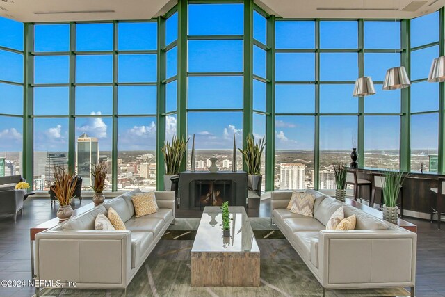 living area featuring expansive windows, a high ceiling, wood finished floors, plenty of natural light, and a city view