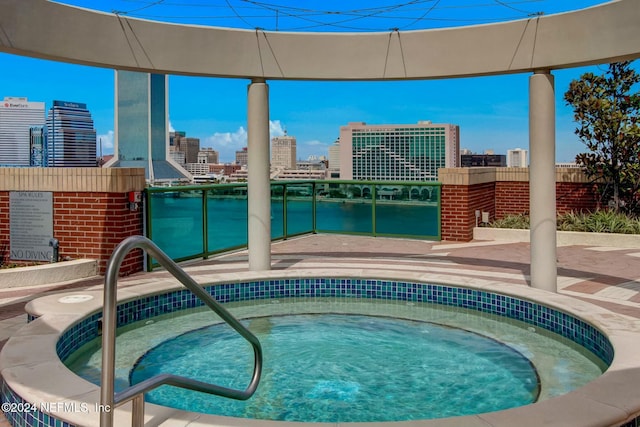 view of pool with a hot tub, a view of city, and a water view