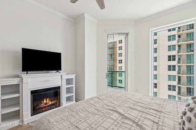 bedroom with ornamental molding, a glass covered fireplace, and ceiling fan