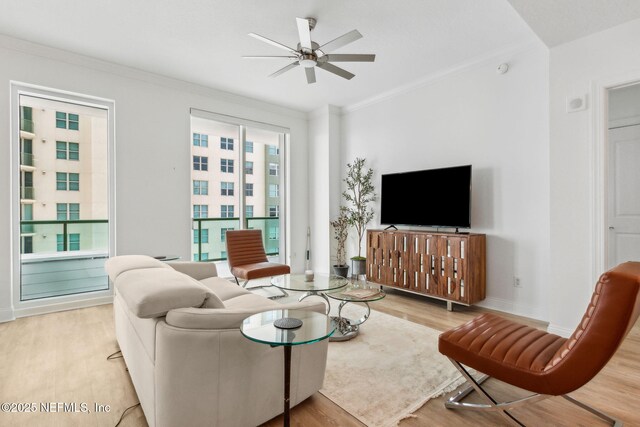 living room with light wood-style floors, ceiling fan, crown molding, and baseboards