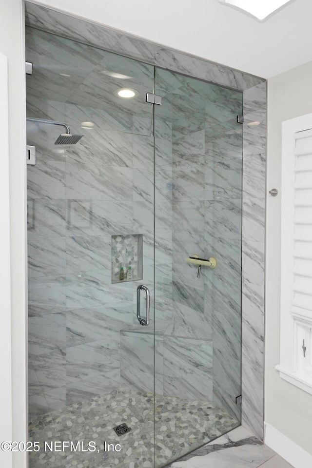 full bath with a shower stall, baseboards, and marble look tiles