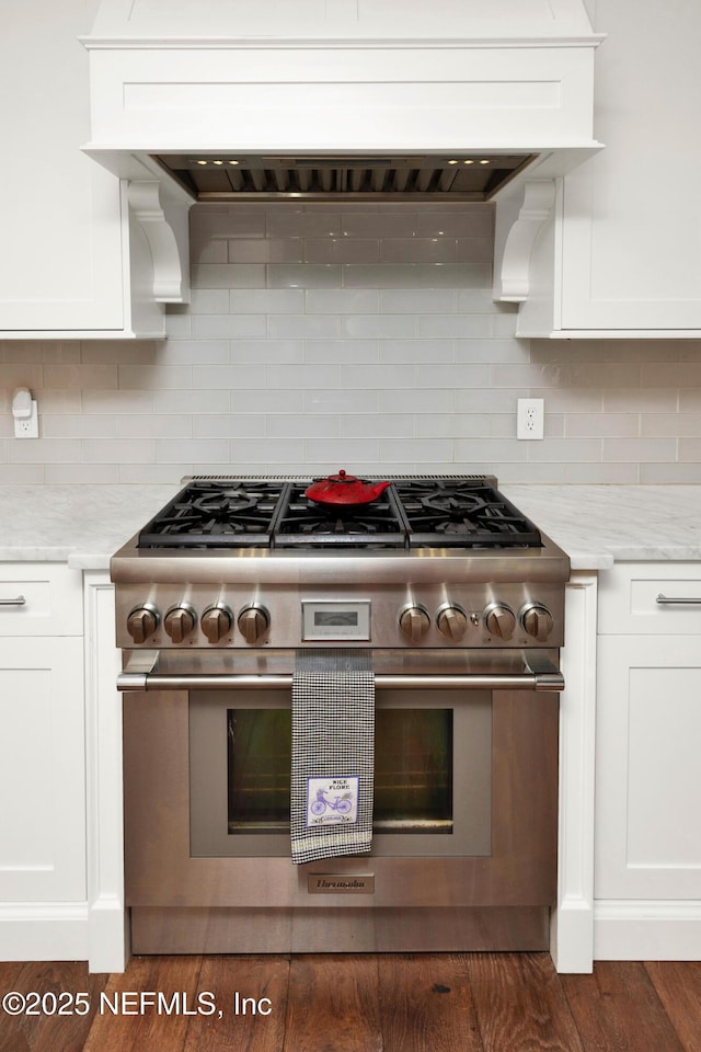 kitchen with high end stainless steel range oven, white cabinetry, backsplash, and dark wood-type flooring