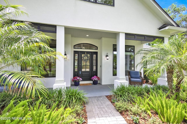 view of exterior entry featuring stucco siding and a porch