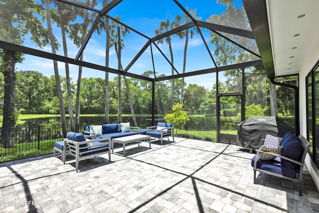 view of patio / terrace featuring an outdoor hangout area, a lanai, fence, a grill, and view of wooded area