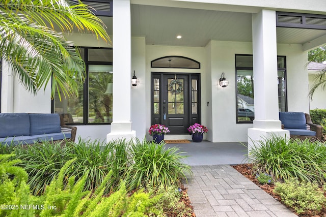 doorway to property with stucco siding, covered porch, and an outdoor living space