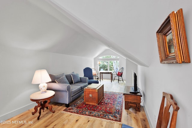 living room featuring light wood-style flooring, lofted ceiling, and baseboards