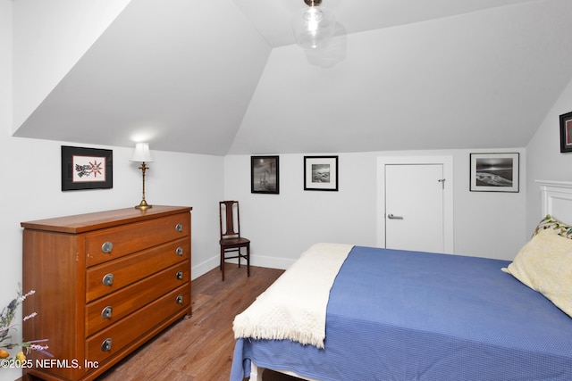 bedroom featuring lofted ceiling, wood finished floors, and baseboards
