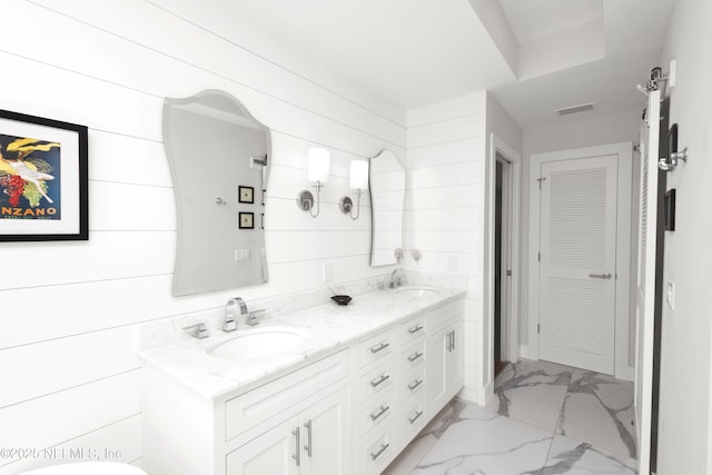 bathroom with marble finish flooring, double vanity, and a closet
