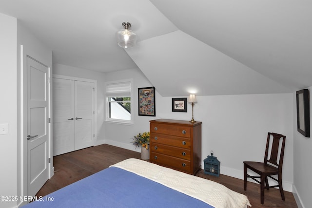 bedroom featuring dark wood-type flooring, baseboards, a closet, and vaulted ceiling