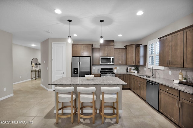 221 Broomsedge Cir, Saint Augustine, FL 32095 - kitchen with appliances with stainless steel finishes, a sink, tasteful backsplash, a center island, and light stone counters