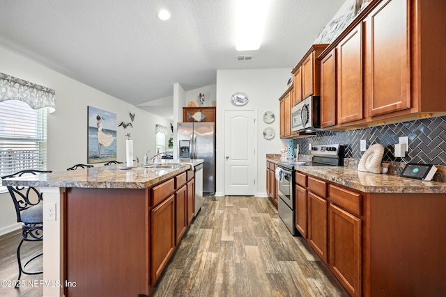 499 Ashby Landing Way, Saint Augustine, FL 32086 - kitchen with appliances with stainless steel finishes, vaulted ceiling, a sink, dark wood-style flooring, and a breakfast bar