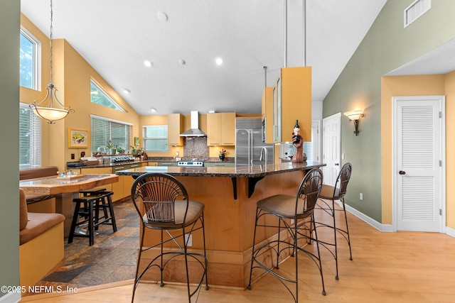 224 Bowles St, Neptune Beach, FL 32266 - kitchen featuring wall chimney exhaust hood, high vaulted ceiling, stainless steel built in fridge, a breakfast bar area, and baseboards