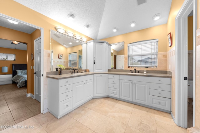 224 Bowles St, Neptune Beach, FL 32266 - bathroom featuring connected bathroom, double vanity, a textured ceiling, vaulted ceiling, and tile patterned flooring