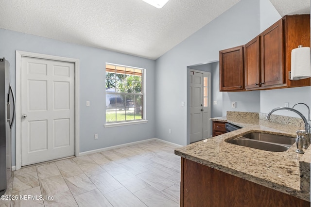 952 Long Lake Dr, Jacksonville, FL 32225 - kitchen featuring a sink, vaulted ceiling, light stone counters, a textured ceiling, and baseboards