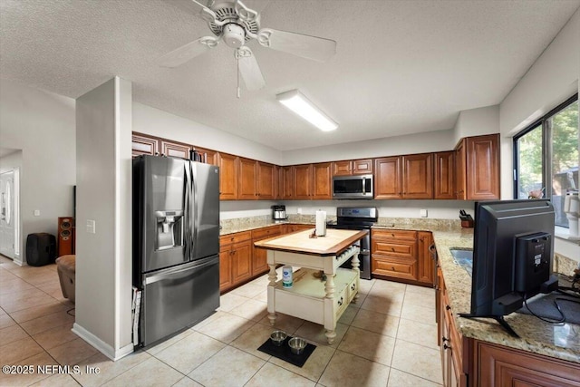 2438 Sylvan Chase Dr, Orange Park, FL 32073 - kitchen featuring stainless steel appliances, brown cabinets, a ceiling fan, light tile patterned floors, and a textured ceiling