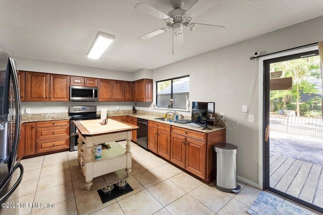 2438 Sylvan Chase Dr, Orange Park, FL 32073 - kitchen with black appliances, brown cabinetry, a textured ceiling, light tile patterned flooring, and a sink