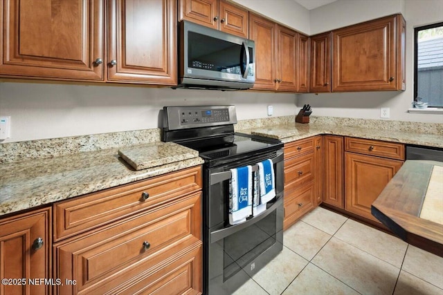 2438 Sylvan Chase Dr, Orange Park, FL 32073 - kitchen with stainless steel appliances, brown cabinets, light stone countertops, and light tile patterned floors