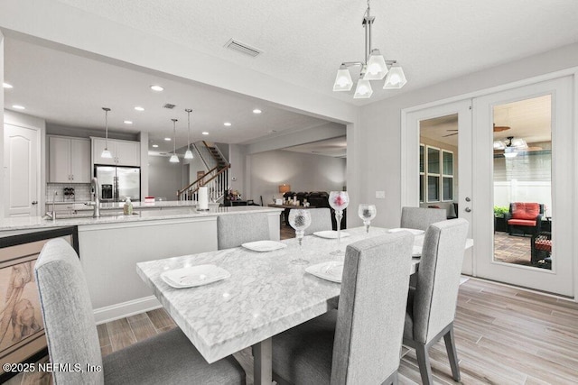 dining space with light wood-style flooring, recessed lighting, and stairs