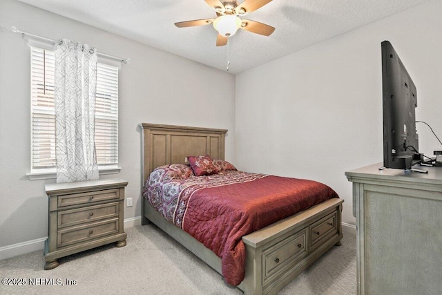 bedroom featuring light colored carpet, baseboards, and a ceiling fan