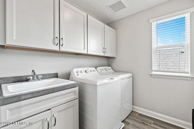 laundry area with washing machine and dryer, cabinet space, dark wood-type flooring, and baseboards