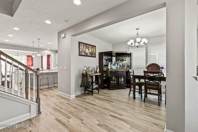 dining room featuring a chandelier, baseboards, wood finished floors, a dry bar, and recessed lighting