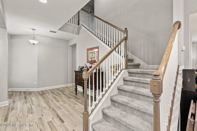 staircase featuring wood finished floors, baseboards, and a textured ceiling