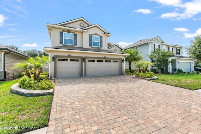 traditional home featuring a garage, stucco siding, a front lawn, and decorative driveway