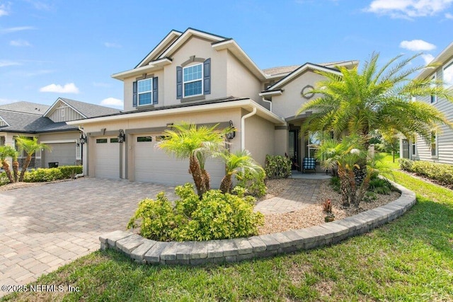 view of front of home with an attached garage, stucco siding, and decorative driveway