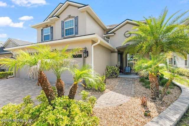 view of front facade with stucco siding, driveway, and a garage