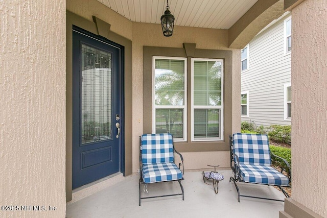 view of exterior entry with stucco siding and a porch