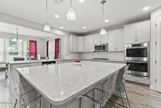 kitchen featuring appliances with stainless steel finishes, recessed lighting, a peninsula, decorative backsplash, and a sink