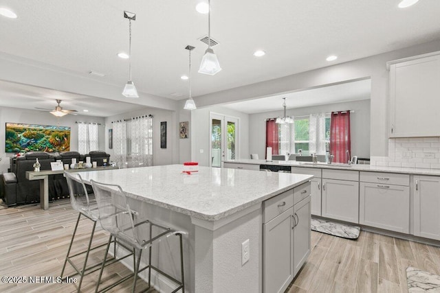 kitchen with a center island, open floor plan, light wood-style floors, recessed lighting, and tasteful backsplash