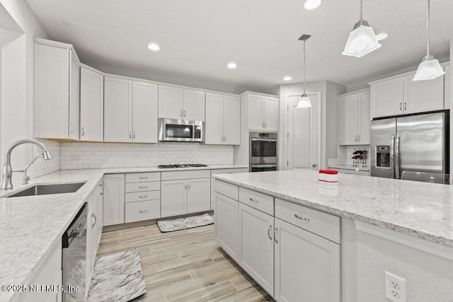 kitchen with appliances with stainless steel finishes, a sink, decorative backsplash, white cabinetry, and recessed lighting