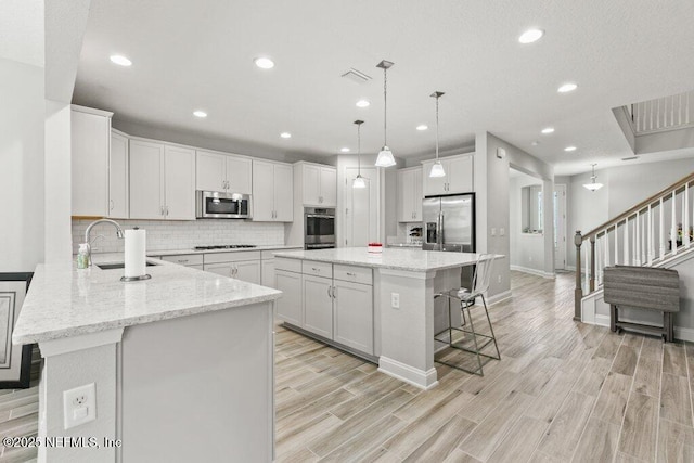 kitchen with stainless steel appliances, a sink, a breakfast bar, decorative backsplash, and recessed lighting