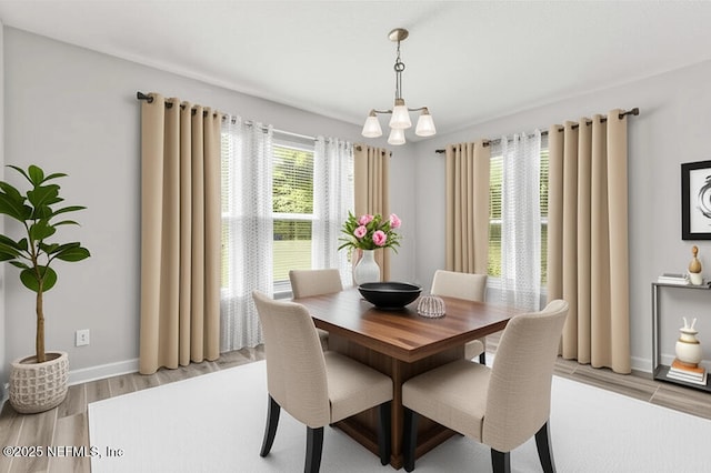 dining space featuring a chandelier, light wood finished floors, and baseboards