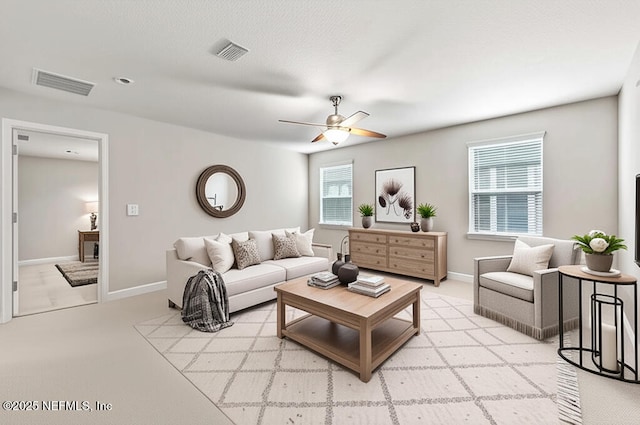 living area featuring a ceiling fan, light carpet, and baseboards