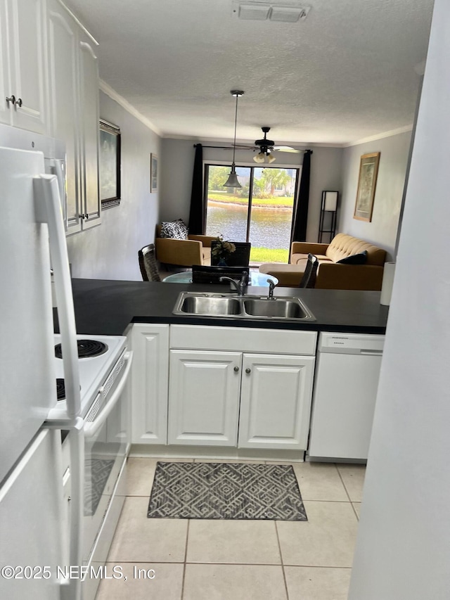 kitchen featuring a sink, white appliances, dark countertops, a peninsula, and crown molding