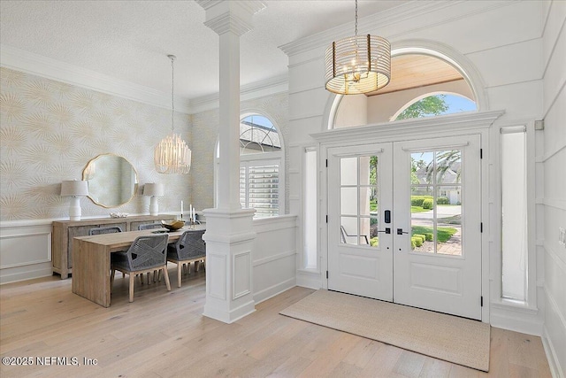 201 Royal Tern Rd N, Ponte Vedra Beach, FL 32082 - foyer entrance with wallpapered walls, a chandelier, a decorative wall, decorative columns, and light wood-style flooring