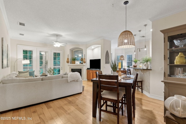 95050 Barclay Pl Unit 5B, Fernandina Beach, FL 32034 - dining area with a textured ceiling, light wood finished floors, crown molding, a ceiling fan, and a fireplace