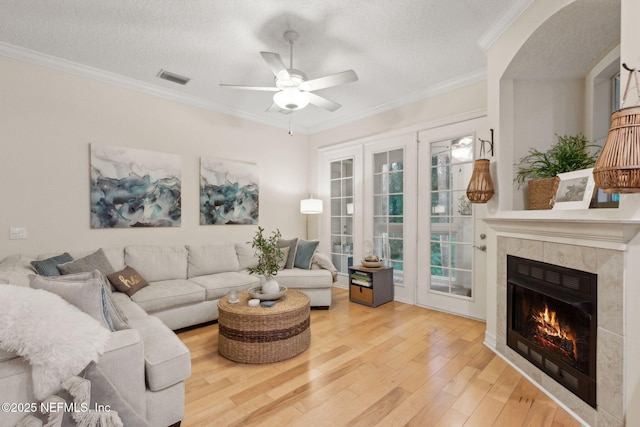 95050 Barclay Pl Unit 5B, Fernandina Beach, FL 32034 - living room featuring wood finished floors, a ceiling fan, a fireplace, ornamental molding, and a textured ceiling