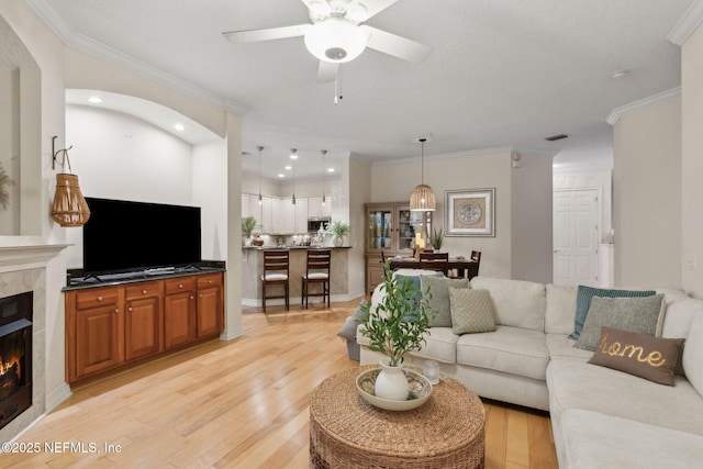95050 Barclay Pl Unit 5B, Fernandina Beach, FL 32034 - living room featuring a tile fireplace, a ceiling fan, light wood finished floors, crown molding, and recessed lighting