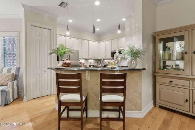 95050 Barclay Pl Unit 5B, Fernandina Beach, FL 32034 - kitchen with stainless steel refrigerator, ornamental molding, dark countertops, light wood-style floors, and a kitchen breakfast bar