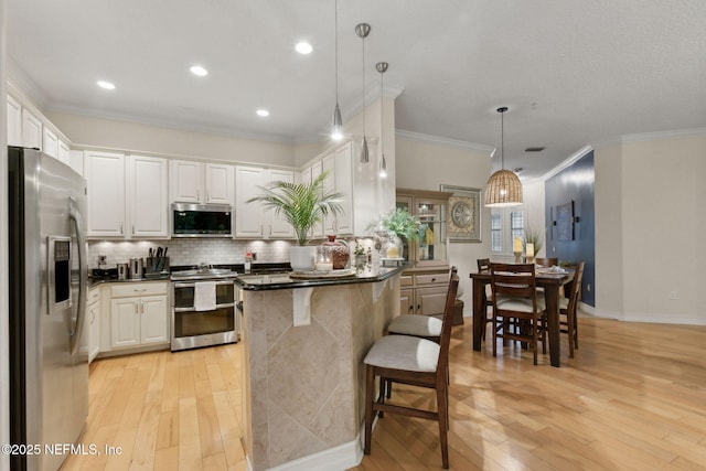 95050 Barclay Pl Unit 5B, Fernandina Beach, FL 32034 - kitchen with appliances with stainless steel finishes, light wood-type flooring, dark countertops, tasteful backsplash, and ornamental molding