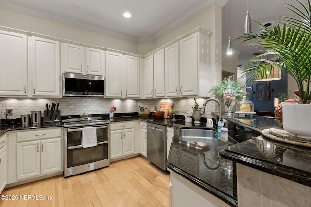 95050 Barclay Pl Unit 5B, Fernandina Beach, FL 32034 - kitchen featuring stainless steel appliances, a sink, white cabinets, light wood-style floors, and ornamental molding