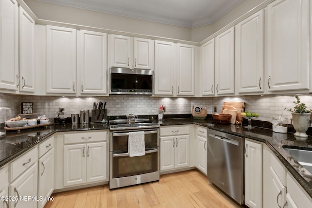 95050 Barclay Pl Unit 5B, Fernandina Beach, FL 32034 - kitchen featuring appliances with stainless steel finishes, white cabinetry, ornamental molding, light wood-type flooring, and backsplash